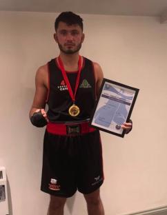 Boxer holding a gold medal and award certificate.