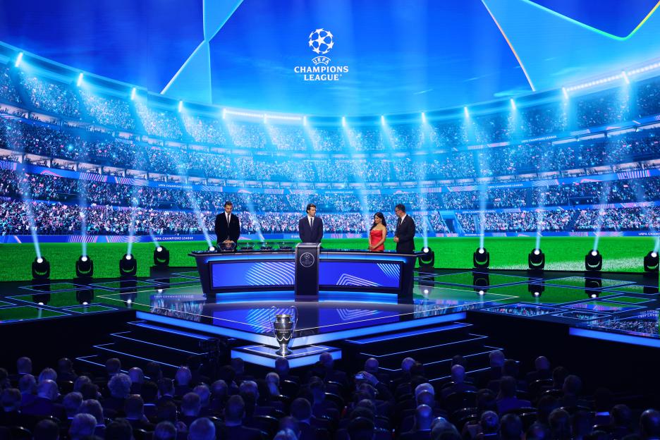 UEFA Champions League draw ceremony stage with presenters and audience.