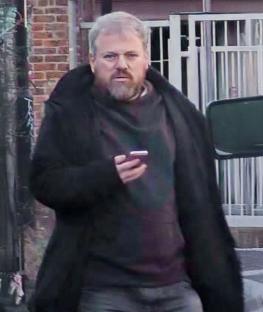Man in dark coat using a cell phone.