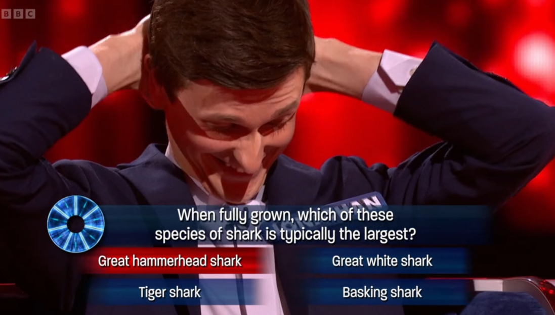 Contestant laughing while answering a question about the largest shark species.
