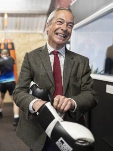 Nigel Farage holding boxing gloves at a boxing gym.