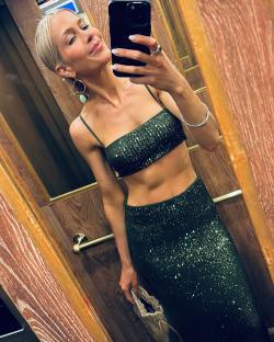 Woman in a dark green sequined crop top and skirt taking a selfie.