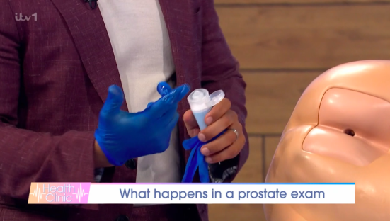 A person demonstrating a prostate exam using a model.