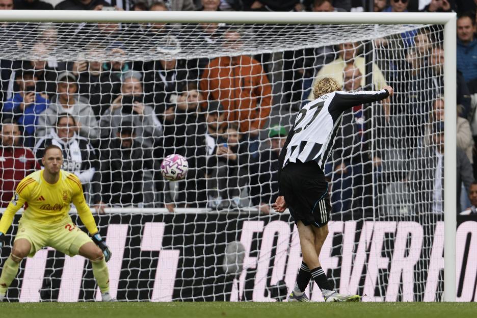 Nick Woltemade of Newcastle United scores a penalty kick, with the ball flying into the net and the goalkeeper looking on.
