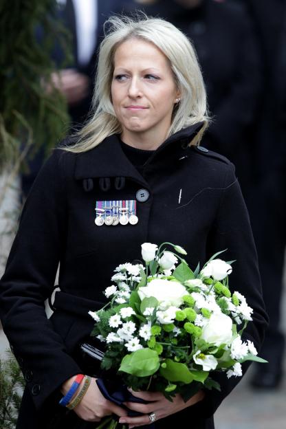 Christina Schmid, wearing her late husband's medals and holding white flowers at his memorial service.