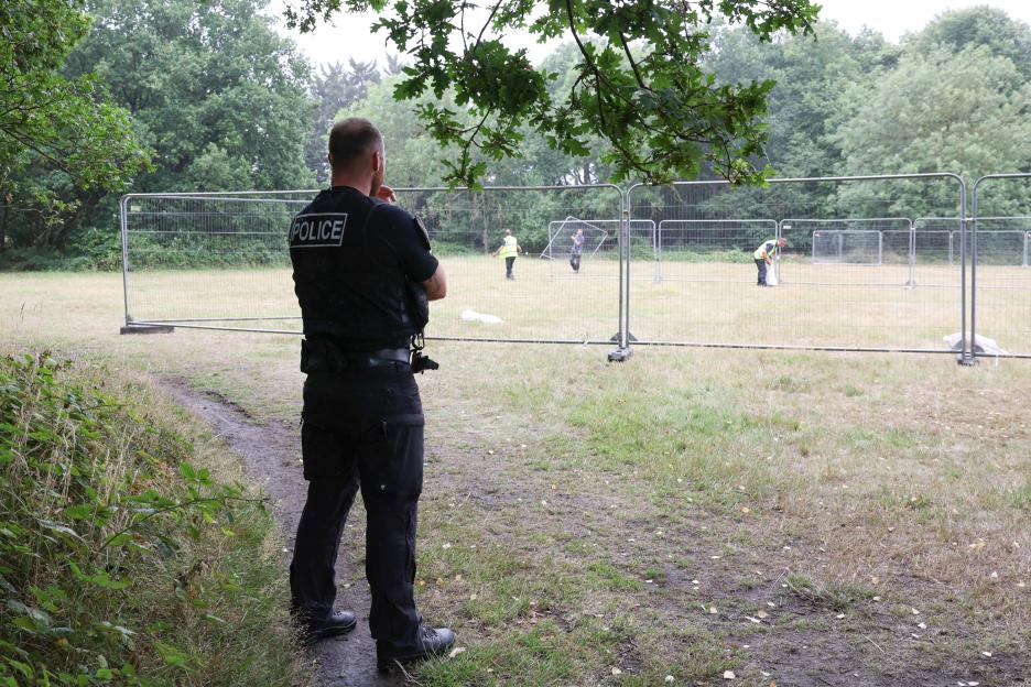 Police officer observing construction of barriers on common land.