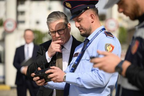 A man in a suit listens as a drone operator explains procedures.