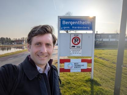 A man stands in front of a Bergentheim, Netherlands sign.