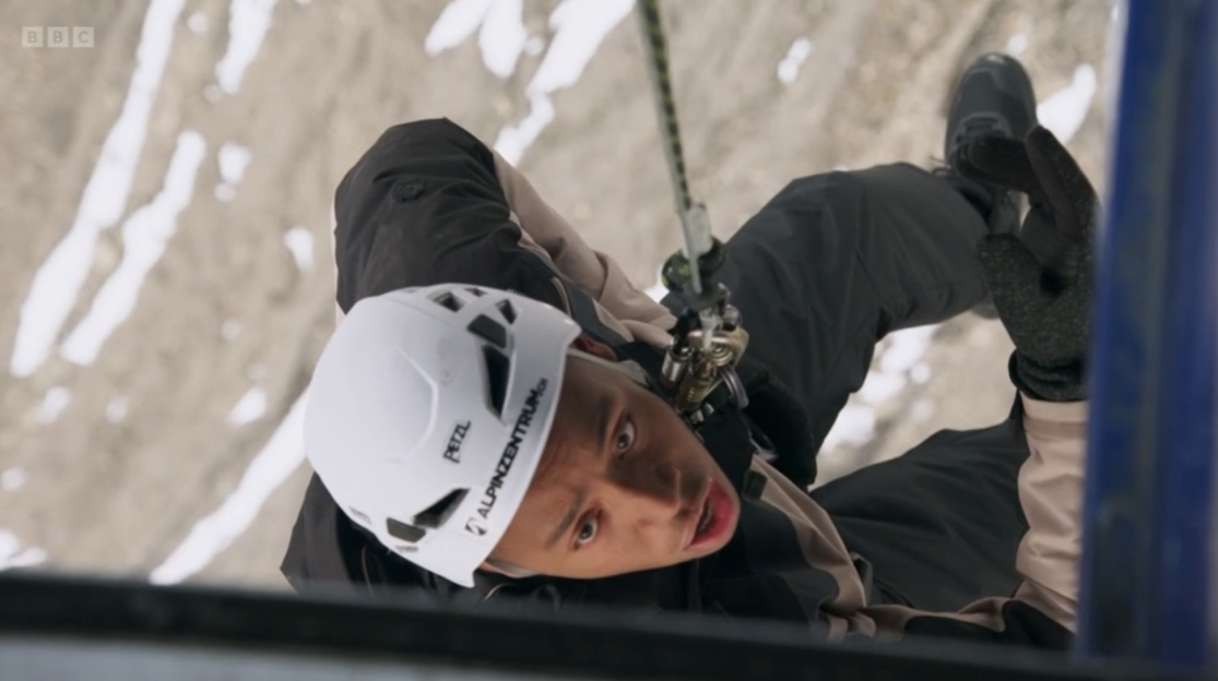 Person rappelling down a cliff face.