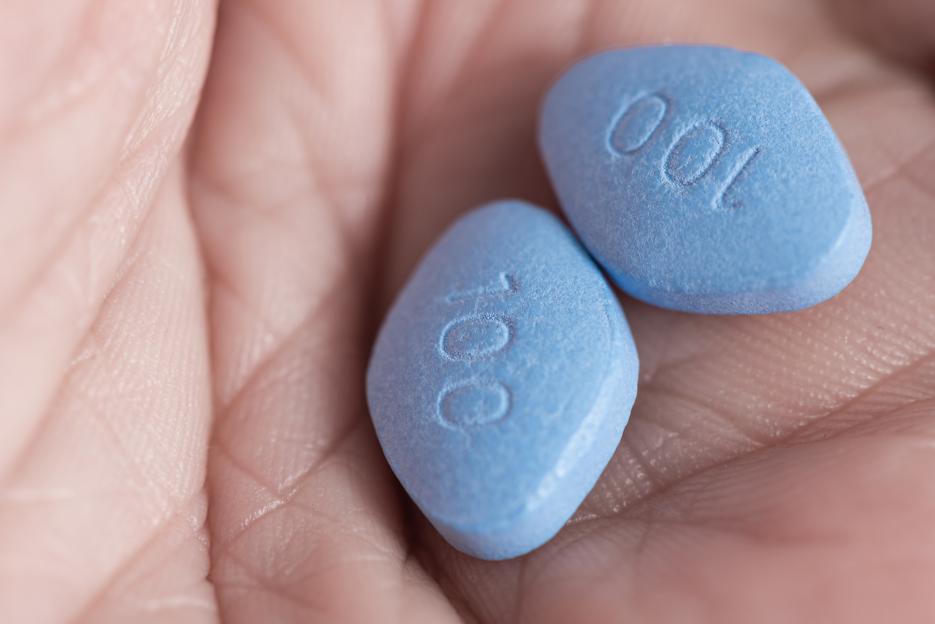 Two blue pills in a person's hand.