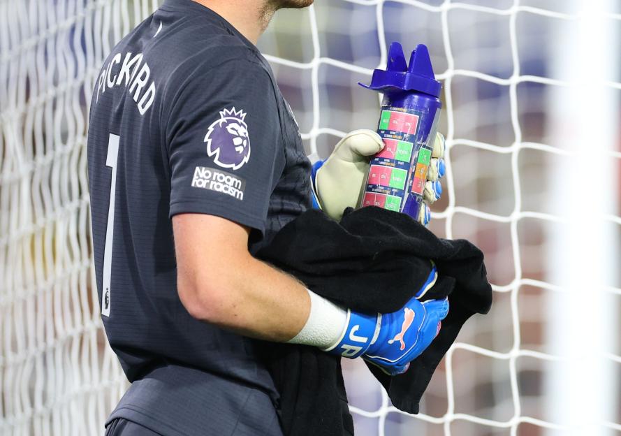 Everton's Jordan Pickford looking at notes on his water bottle.