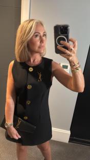 Woman in black dress taking a selfie.