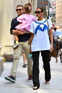 Irina Shayk, Bradley Cooper, and their daughter walking down a city street.