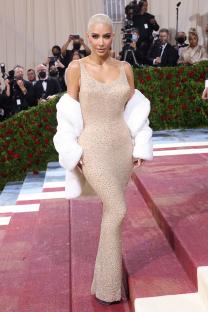 Kim Kardashian at the Met Gala in a beige, embellished gown and white fur jacket.