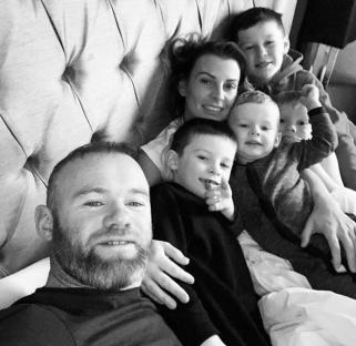 Black and white photo of Coleen and Wayne Rooney with their sons in bed.