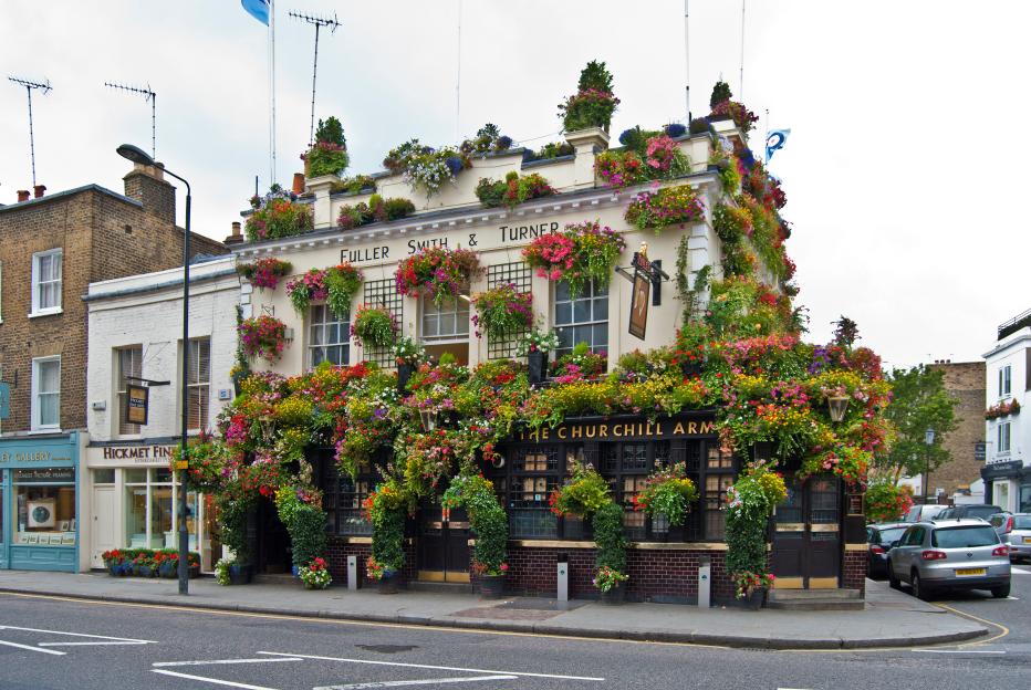 The Churchill Arms pub on Kensington Church Street, London, heavily adorned with colorful flowers and plants.