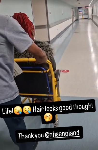 Woman in wheelchair being pushed down hospital corridor.