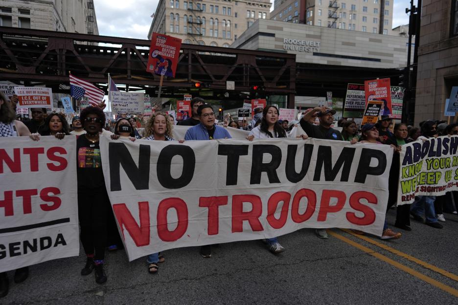 Protestors march with a banner reading "No Trump No Troops".
