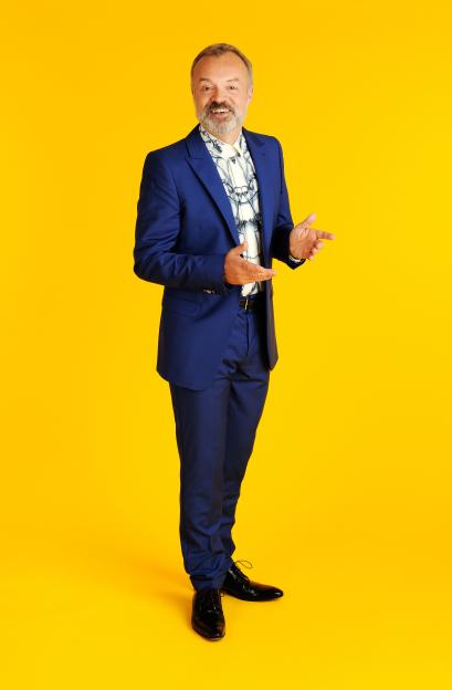 Graham Norton in a blue suit against a yellow background.