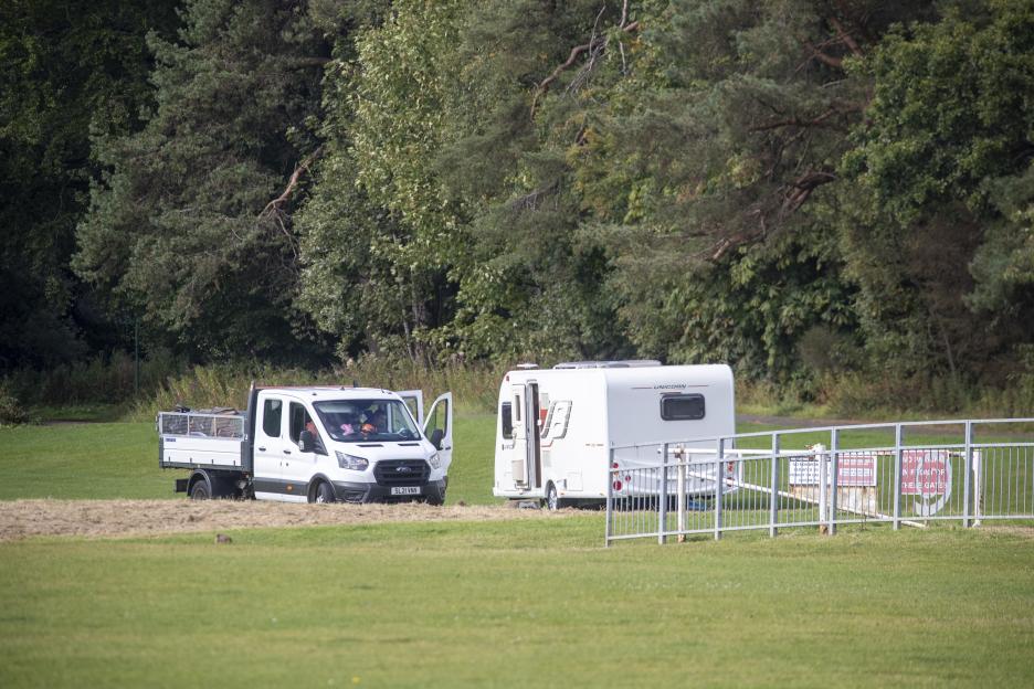 A white van and caravan parked in a park.