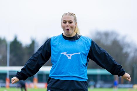 Woman in blue athletic vest with arms outstretched.
