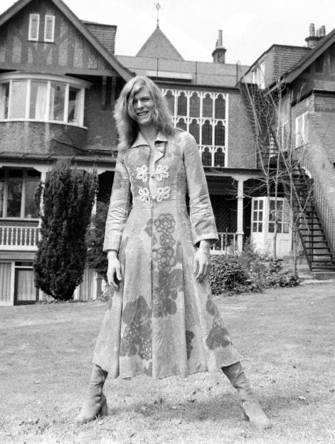David Bowie in a floral patterned long coat standing in front of Haddon Hall.