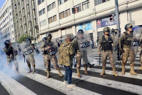 Police officers in riot gear face off against a civilian during a protest in Lima, Peru.