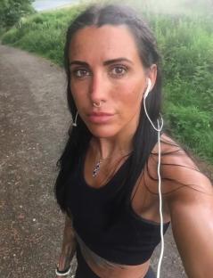 Woman wearing earbuds and athletic wear outdoors.