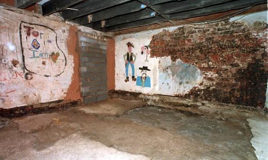 Basement of 25 Cromwell Street with graffiti and damaged walls.
