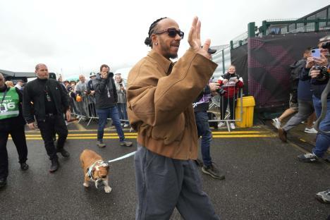 Lewis Hamilton waving to fans while walking his dog.