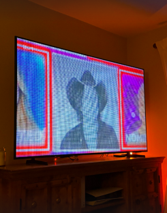 Television screen displaying a glitching image of a person wearing a hat.