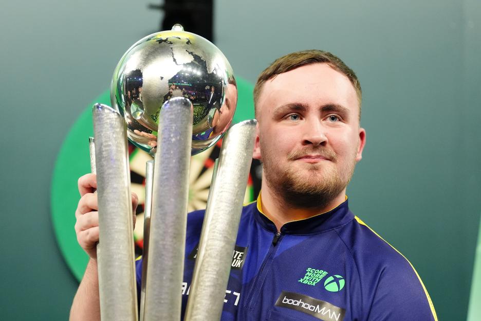 Luke Littler holding The Sid Waddell Trophy.