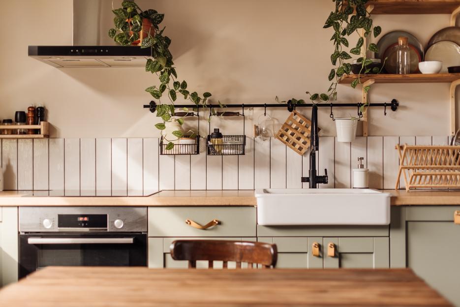 Kitchen with a black Aga range cooker, grey cabinets, a wooden island with stools, and decorative plates on the walls.