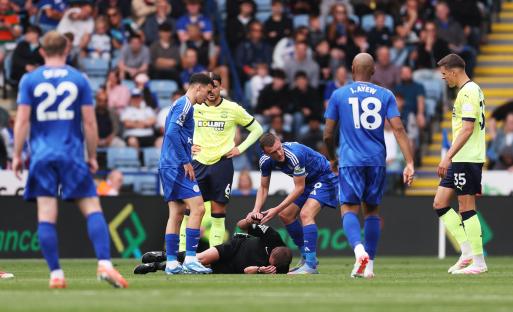 Jamie Vardy of Leicester City attending to an injured referee on the field.