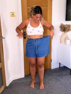 Woman showing how stretchy her denim shorts are.