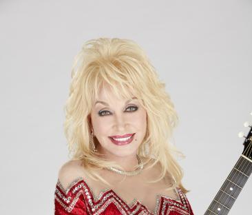 Dolly Parton in a red sequined dress, holding a guitar.