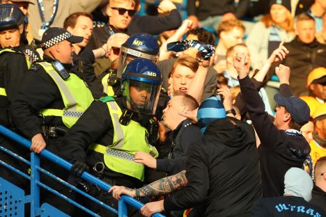 Police officers confronting Djurgarden fans at a soccer match.