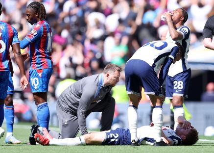 Dejan Kulusevski of Tottenham Hotspur receiving medical attention on the field.