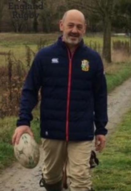 Man in England Rugby jacket carrying a rugby ball.