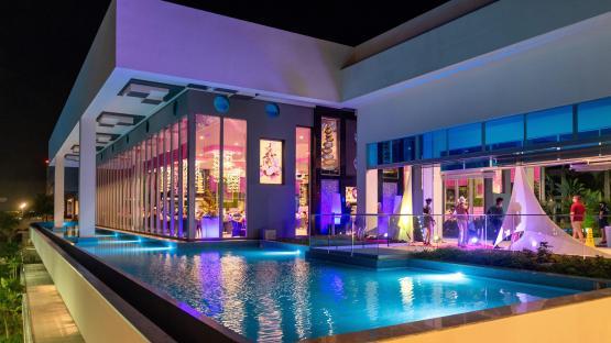 Hotel Riu Palace Costa Mujeres at night, with a pool and illuminated restaurant.
