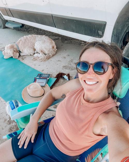 Woman smiling while sitting in a chair outdoors with her dog.