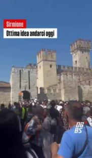Large crowd of tourists in Sirmione, Italy, in front of a castle.