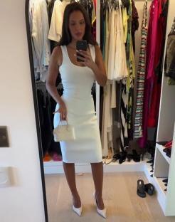 Woman in white dress taking a selfie in front of a mirror in her closet.