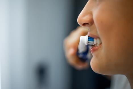 Teenage boy brushing his teeth with an electric toothbrush.