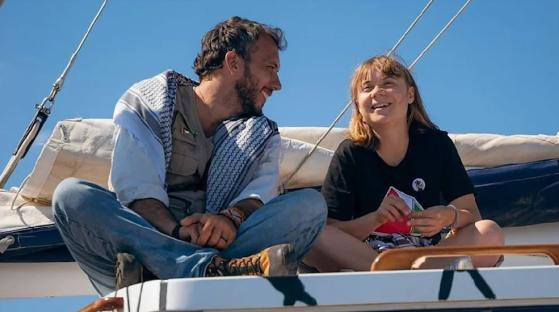 Greta Thunberg and a crew member sitting on a boat.
