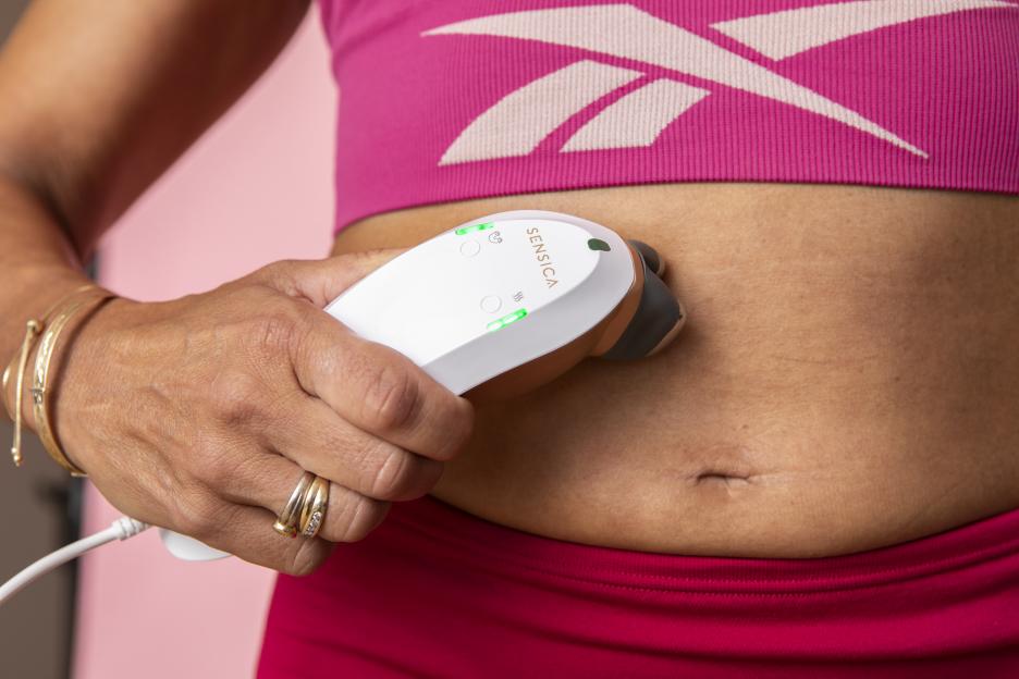Woman using a Sensica device on her abdomen.