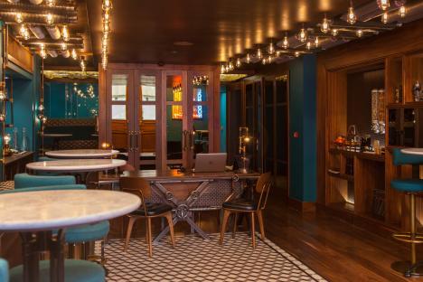 Hotel lobby with teal walls, marble-top tables, and steampunk-style lighting.