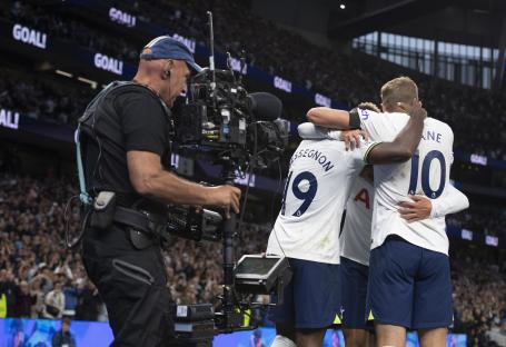 Tottenham Hotspur players celebrating a goal while a cameraman films.