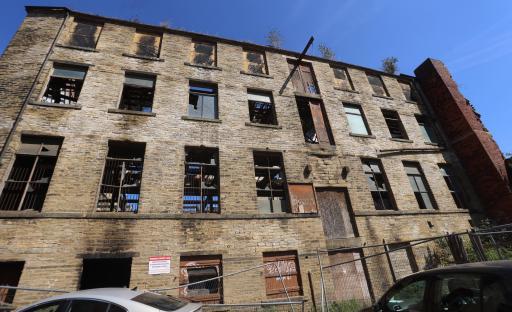 Derelict stone building with broken windows and boarded doors.