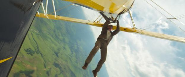 Tom Cruise as Ethan Hunt hanging from a biplane.